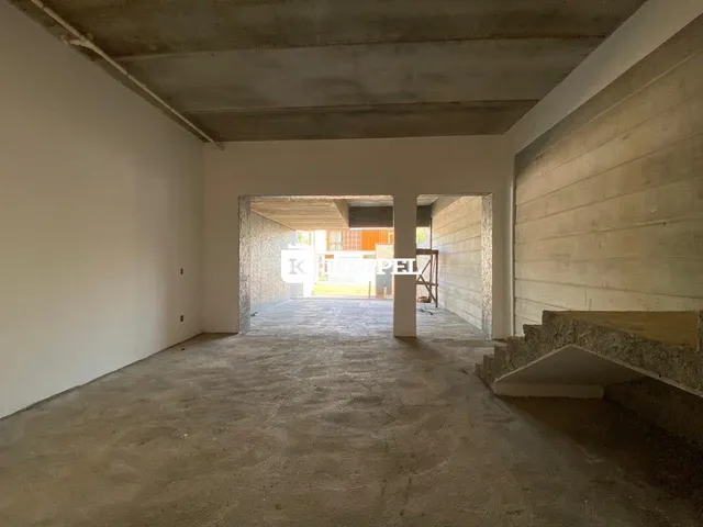 Interior de um espaço com teto de concreto aparente e paredes brancas.