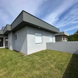 Fachada de uma casa moderna com telhado plano e jardim gramado em Lajeado.