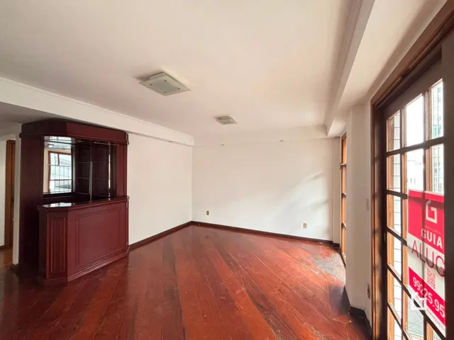 Ambiente interno com piso de madeira polida e parede branca.