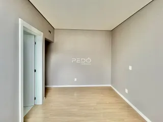 Interior de um ambiente com piso de madeira clara e paredes cinzas.