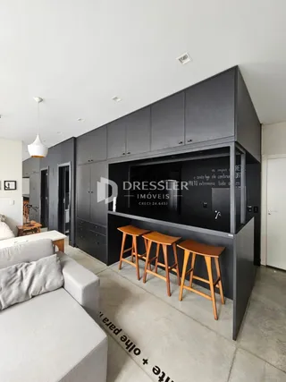 Sala de estar com sofá claro e armários escuros.