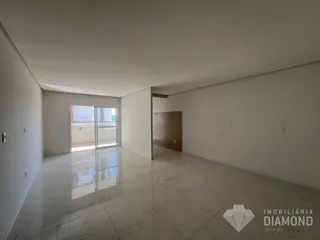Foto de uma sala ampla e vazia com piso claro e paredes brancas.