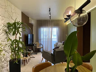 Sala de estar com cortinas claras e plantas grandes.