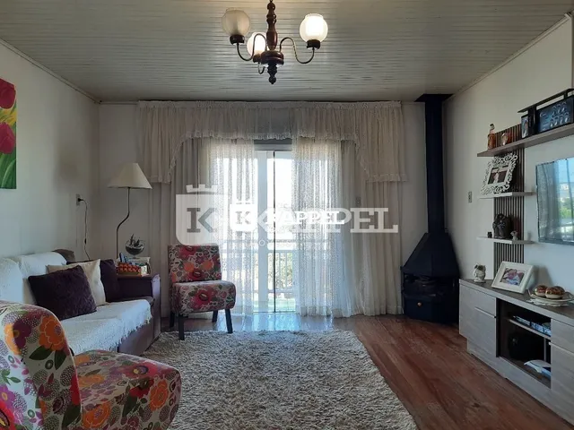 Uma sala de estar clara com cortinas brancas e piso de carpete.
