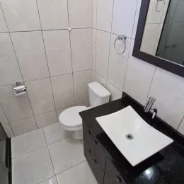 Foto de um banheiro com revestimento de azulejos brancos e louças sanitárias.
