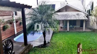 Vista externa de uma propriedade com deck de madeira e gramado.