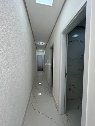 Corredor interno com piso de mármore claro e paredes brancas.