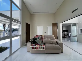 Uma sala de estar clara com sofá e grandes janelas de vidro.