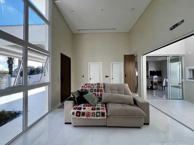 Uma sala de estar clara com sofá e grandes janelas de vidro.