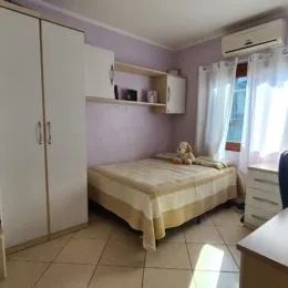 Quarto com cama de casal e paredes claras.