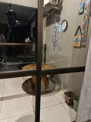 Vista interna de uma sala com piso de cerâmica e uma mesa de madeira.