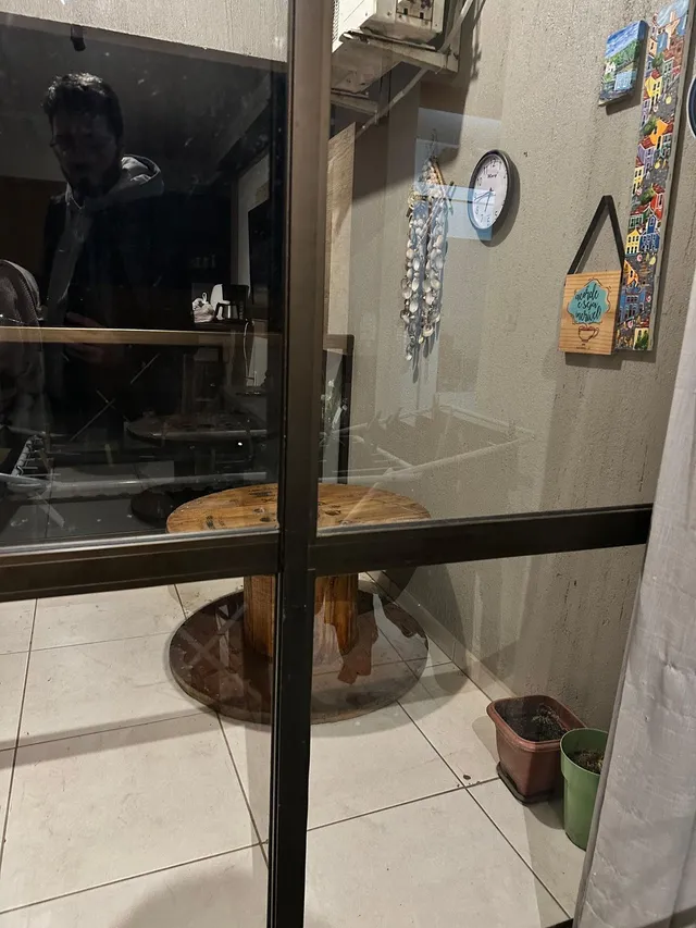 Vista interna de uma sala com piso de cerâmica e uma mesa de madeira.