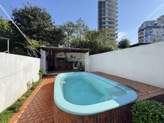 Vista externa de uma área de lazer com uma banheira de hidromassagem em um pátio de tijolos.