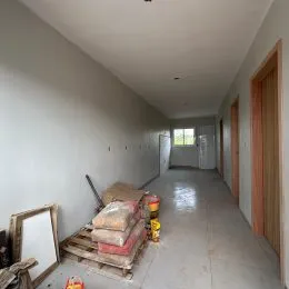 Corredor interno com paredes brancas e materiais empilhados no chão.