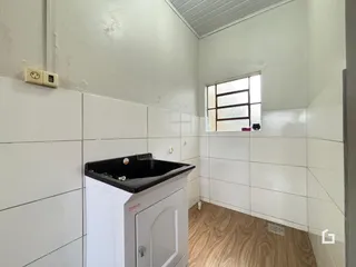 Interior de um ambiente com paredes brancas e piso de madeira.