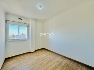 Ambiente interno com piso de madeira e janela de vista para a cidade.
