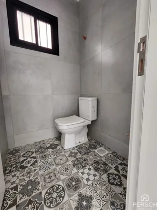 Foto interna de um banheiro com piso de azulejos estampados.
