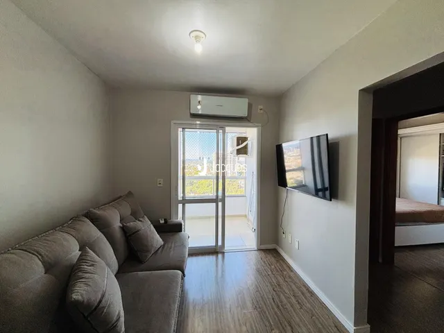 Sala de estar com sofá e porta de vidro abrindo para a varanda.
