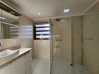 Foto de um banheiro com box de vidro e bancada de pia.