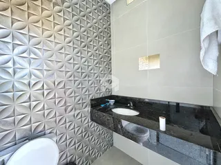 Banheiro com revestimento de azulejos geométricos e bancada escura.