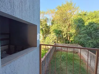 Fachada de uma residência com cerca e vegetação ao fundo.