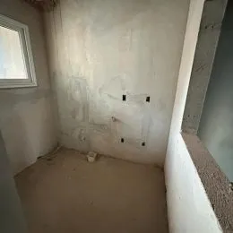 Foto de um cômodo interno com paredes e piso crus.