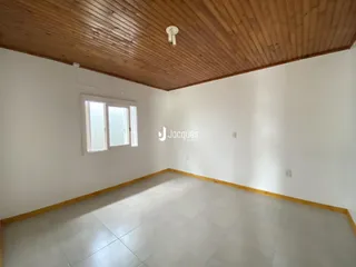 Ambiente interno de uma sala com teto de madeira e piso claro.