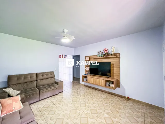 Sala de estar com sofá marrom e painel de TV de madeira.