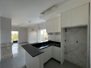 Cozinha moderna com armários brancos e bancadas escuras.