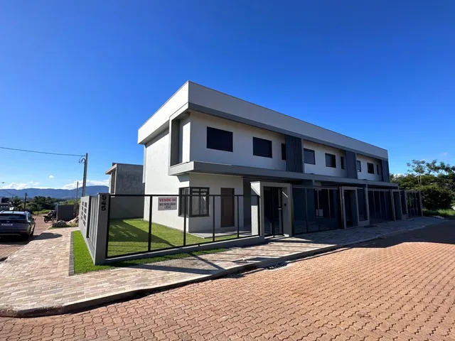 Fachada moderna de uma casa residencial em Lajeado, Brasil, com revestimento claro e detalhes em cinza escuro.