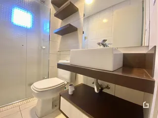 Foto de um banheiro com revestimento cerâmico e box de vidro.