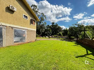 Vista externa de uma casa com jardim gramado e cerca.