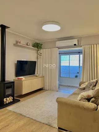 Sala de estar com sofá, televisão e lareira em um apartamento no Brasil.