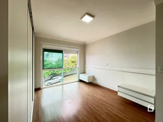 Sala de estar com piso de madeira e grande janela.