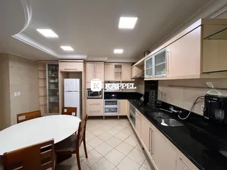 Cozinha moderna com armários claros e bancada escura.