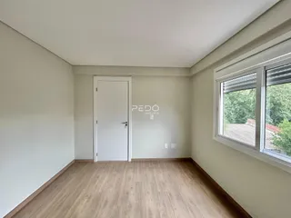 Ambiente interno de uma sala com piso de madeira e janela.