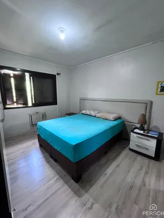 Quarto com cama e piso de madeira clara.