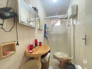 Foto de um banheiro com azulejos brancos e pia de cerâmica.