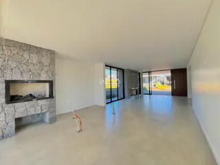 Ambiente interno de uma sala de estar com lareira e portas de vidro.