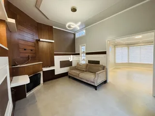 Sala de estar com painéis de madeira e sofá no interior de uma residência.