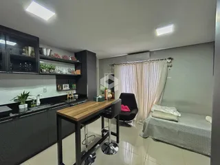 Interior de uma sala de estar com cozinha e área de jantar em um imóvel no Brasil.
