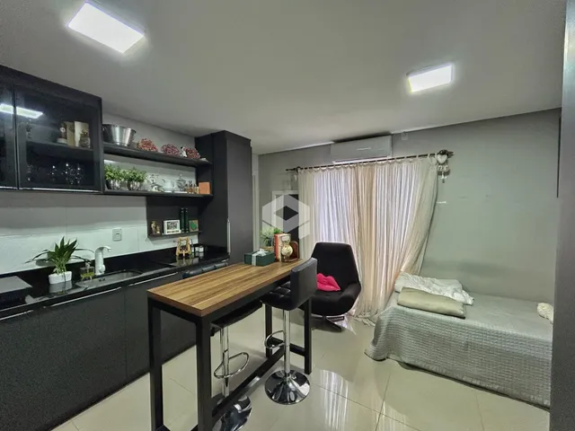 Interior de uma sala de estar com cozinha e área de jantar em um imóvel no Brasil.