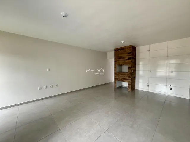 Sala de estar ampla com piso de cerâmica e parede de madeira em um imóvel.