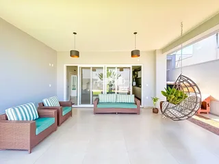 Sala de estar com sofás de vime e portas de vidro que dão acesso ao exterior.