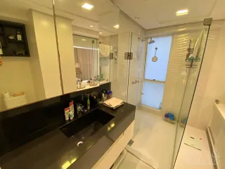 Vista da cozinha com bancadas escuras e armários brancos em um imóvel.