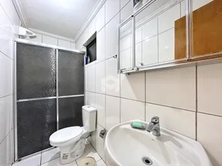 Interior de um banheiro com revestimento cerâmico branco.