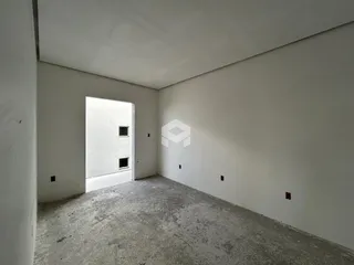 Vista interna de um ambiente com paredes brancas e piso de concreto.