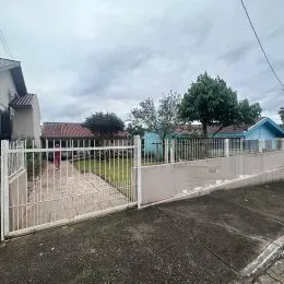 Vista externa da propriedade mostrando uma cerca branca e área gramada.