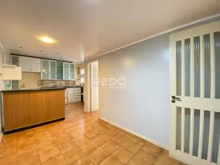 Interior de uma cozinha com piso de cerâmica e armários de madeira.