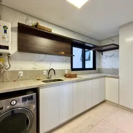 Cozinha com armários brancos e bancada clara.